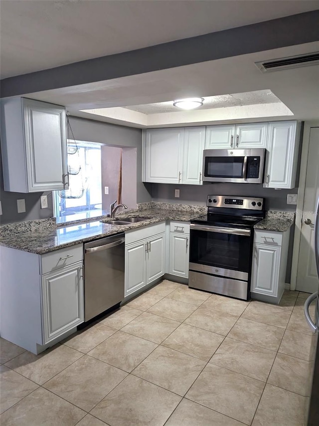 kitchen featuring visible vents, a sink, appliances with stainless steel finishes, light tile patterned flooring, and white cabinets