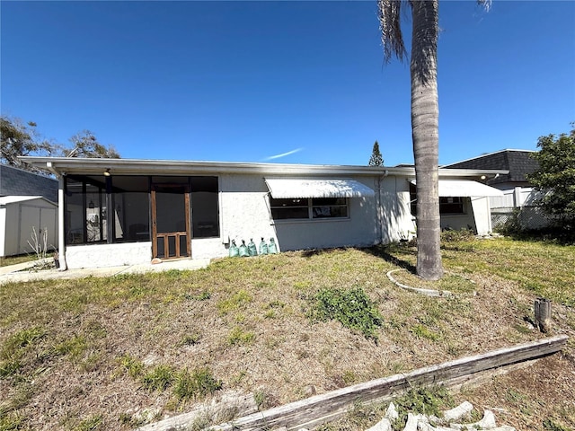 4030 Grayton Dr, New Port Richey, FL 34652 - back of property with a storage shed, stucco siding, an outbuilding, a lawn, and a sunroom