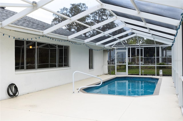 pool featuring glass enclosure and a patio area