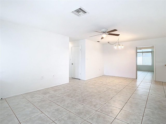 empty room featuring light tile patterned floors, ceiling fan with notable chandelier, and visible vents