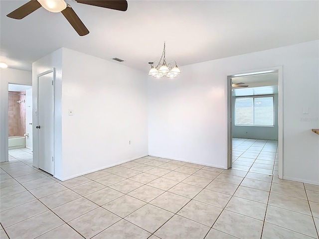 empty room with light tile patterned flooring, ceiling fan with notable chandelier, and visible vents