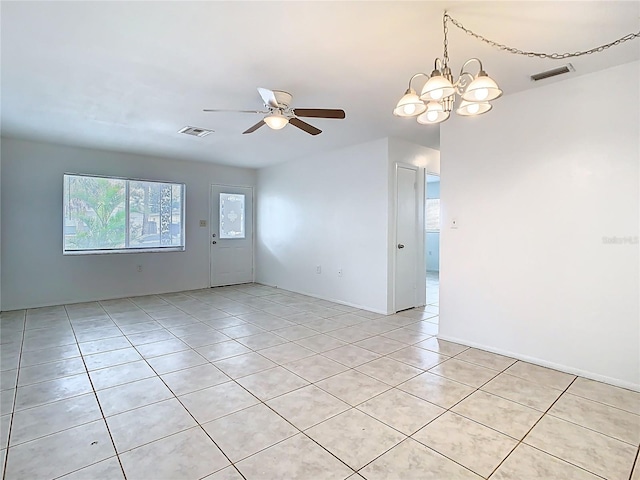 spare room featuring light tile patterned floors, visible vents, and ceiling fan with notable chandelier