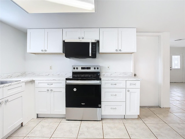 kitchen with visible vents, light tile patterned floors, stainless steel range with electric stovetop, white cabinets, and a sink