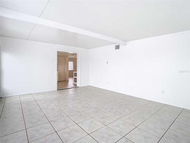 empty room with beam ceiling, light tile patterned floors, and visible vents