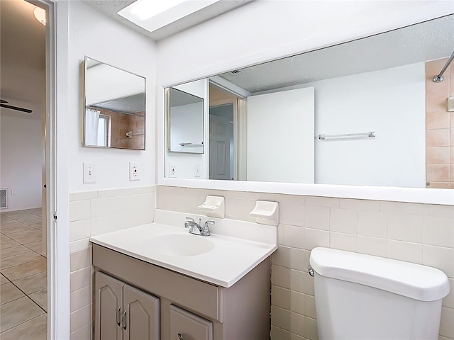 bathroom with visible vents, toilet, tile walls, and vanity