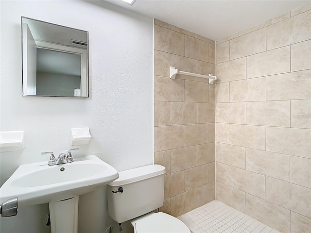 bathroom featuring toilet, a stall shower, and a sink