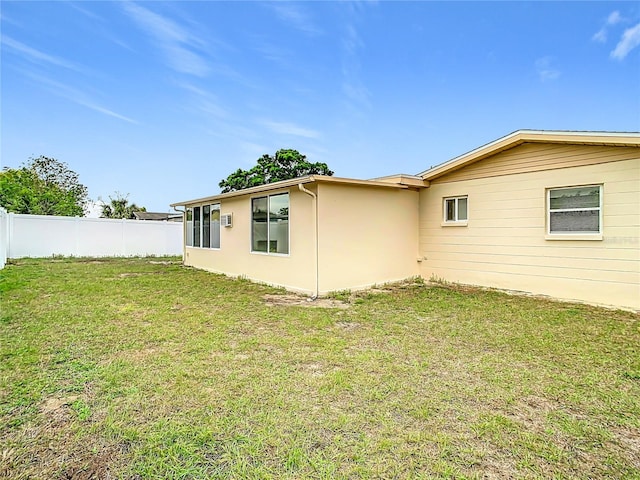 exterior space featuring stucco siding, a lawn, and fence