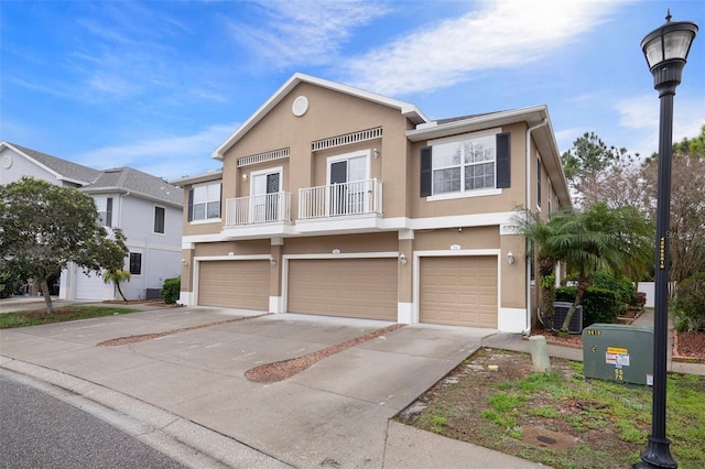 view of front of property with stucco siding, a garage, a balcony, and driveway