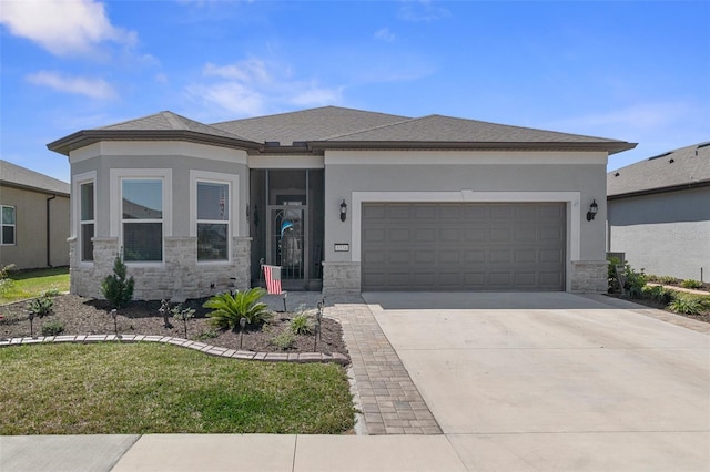 prairie-style house with an attached garage, stone siding, concrete driveway, stucco siding, and a front yard