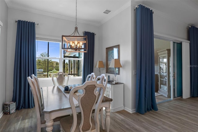 dining room with visible vents, crown molding, baseboards, a chandelier, and wood finished floors