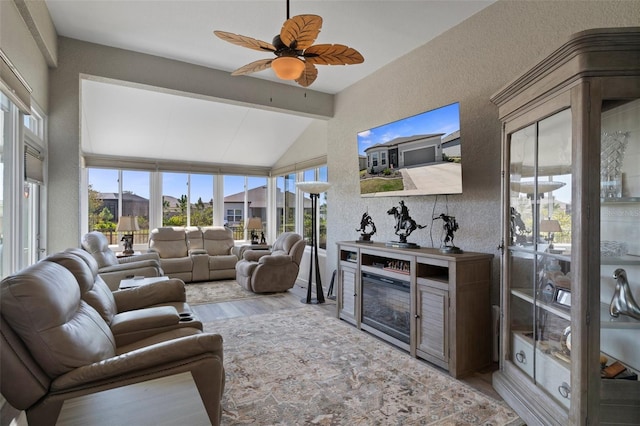 living room featuring lofted ceiling with beams, wood finished floors, a ceiling fan, and a textured wall