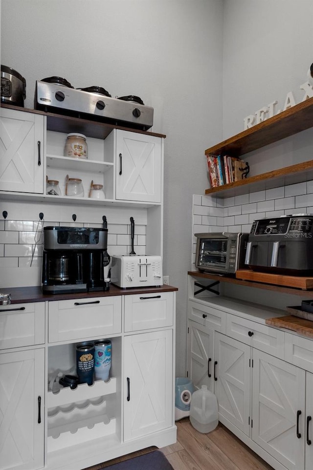 kitchen with backsplash, white cabinets, light wood-type flooring, and open shelves