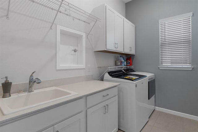 laundry area featuring a sink, baseboards, cabinet space, and washing machine and dryer