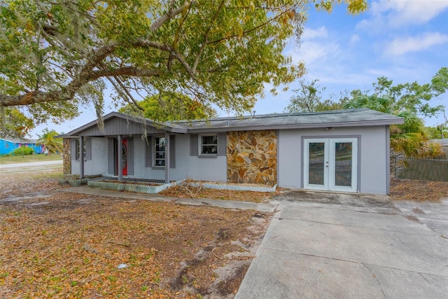 view of front of home with fence, french doors, and stone siding