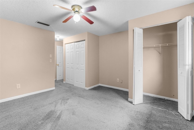 unfurnished bedroom with visible vents, multiple closets, a textured ceiling, carpet flooring, and baseboards