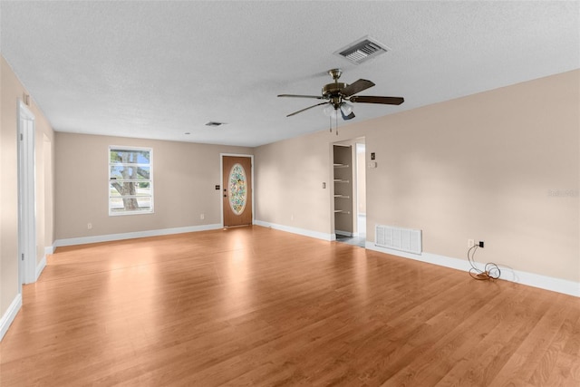 unfurnished living room featuring visible vents, a textured ceiling, and light wood-type flooring