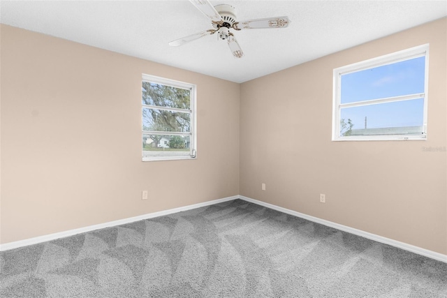 carpeted spare room featuring ceiling fan and baseboards