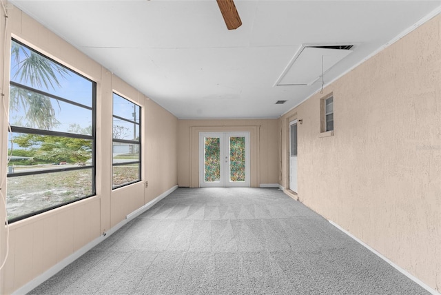 carpeted empty room featuring attic access, a textured wall, and french doors