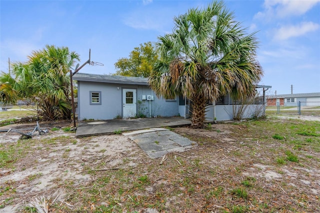 rear view of property with stucco siding, a patio area, and fence