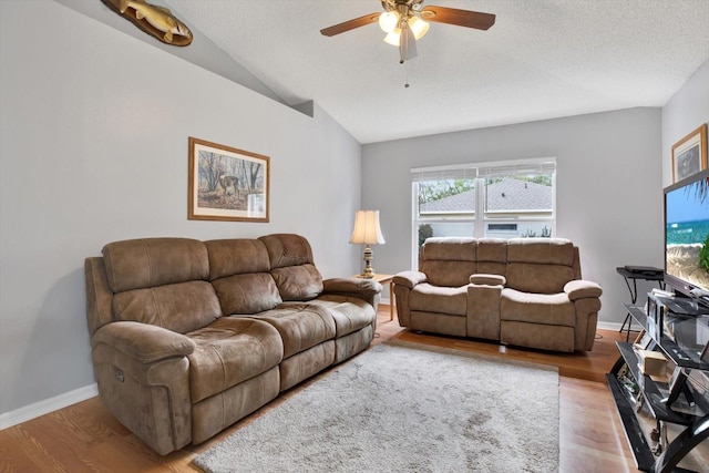 living room with baseboards, a ceiling fan, lofted ceiling, and wood finished floors