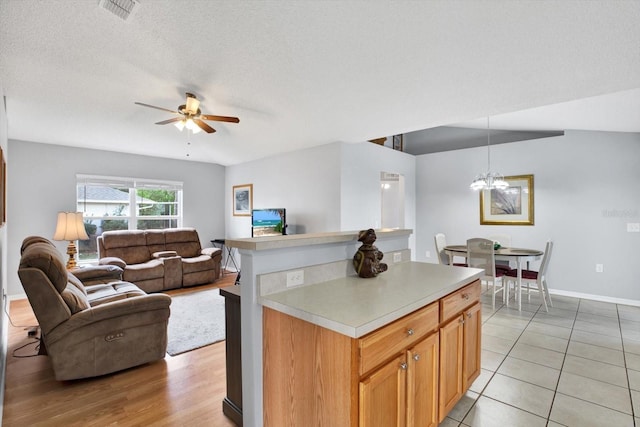 kitchen with light countertops, ceiling fan with notable chandelier, open floor plan, and a textured ceiling