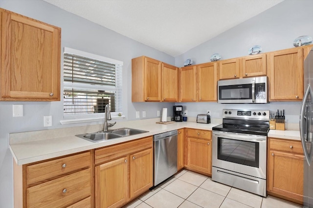 kitchen featuring light countertops, lofted ceiling, light tile patterned floors, appliances with stainless steel finishes, and a sink