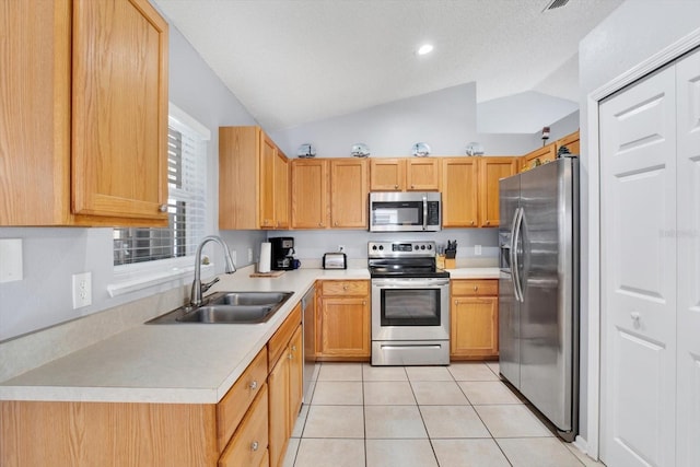 kitchen with light countertops, lofted ceiling, light tile patterned flooring, stainless steel appliances, and a sink