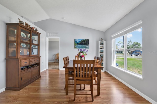 dining area with vaulted ceiling, baseboards, visible vents, and light wood finished floors