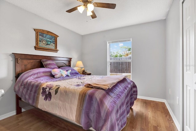 bedroom featuring baseboards, a textured ceiling, and wood finished floors