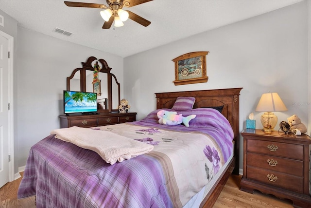 bedroom featuring visible vents, a textured ceiling, ceiling fan, and wood finished floors