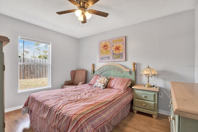 bedroom with baseboards, light wood-type flooring, and a textured ceiling