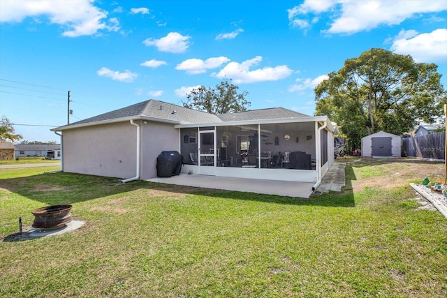 rear view of house featuring a shed, a fire pit, a lawn, and a sunroom