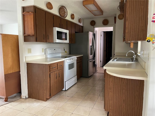 kitchen featuring a sink, white appliances, light tile patterned floors, and light countertops