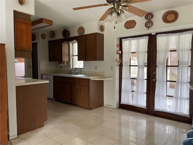 kitchen with dishwashing machine, light countertops, french doors, and a sink