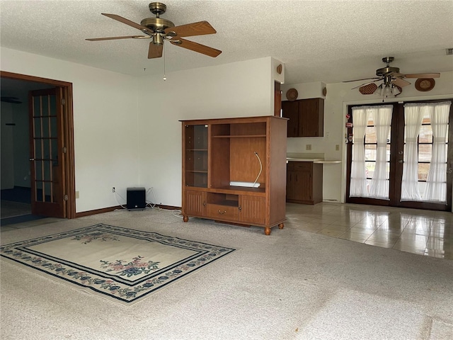 unfurnished living room featuring a ceiling fan, a textured ceiling, french doors, light tile patterned flooring, and light colored carpet