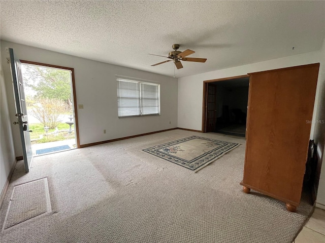 unfurnished living room with light colored carpet, a textured ceiling, baseboards, and a ceiling fan