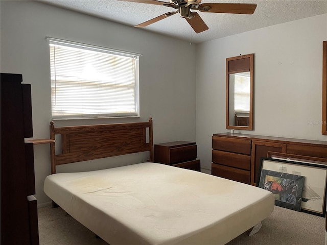 carpeted bedroom featuring a ceiling fan and a textured ceiling