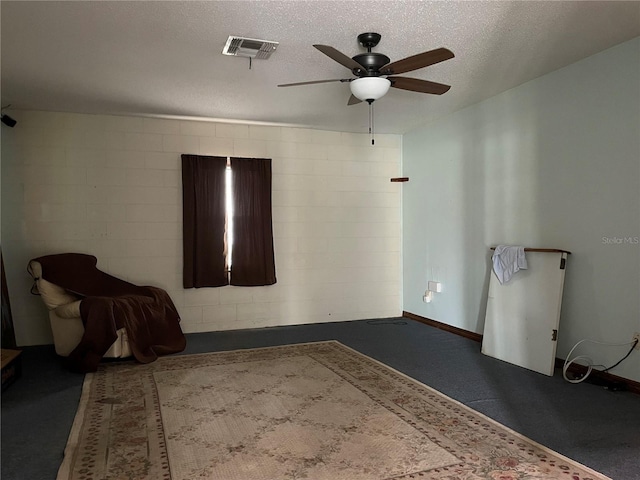 unfurnished room with visible vents, a ceiling fan, a textured ceiling, concrete block wall, and baseboards