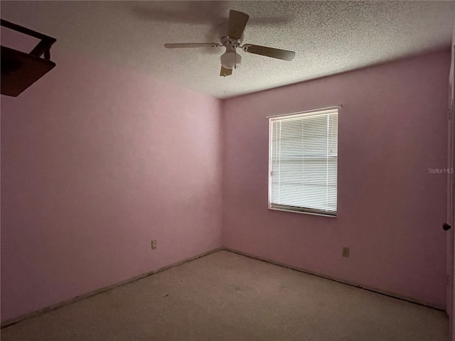 carpeted spare room with a textured ceiling and a ceiling fan