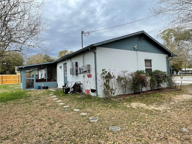 view of home's exterior featuring fence, a yard, and a sunroom