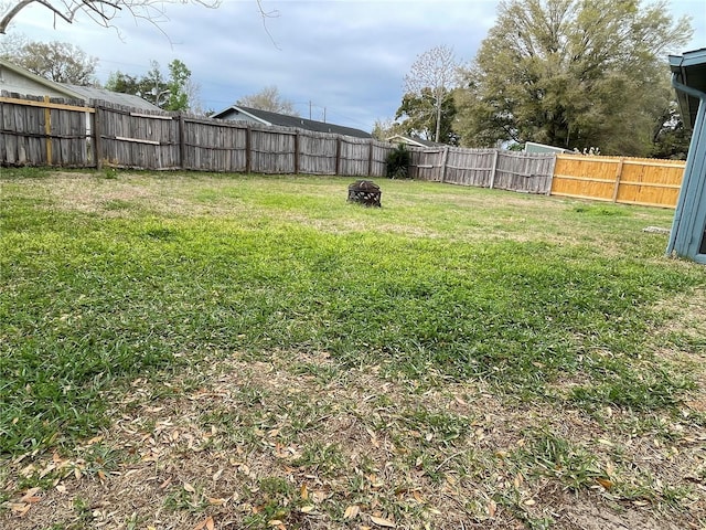 view of yard featuring a fire pit and a fenced backyard