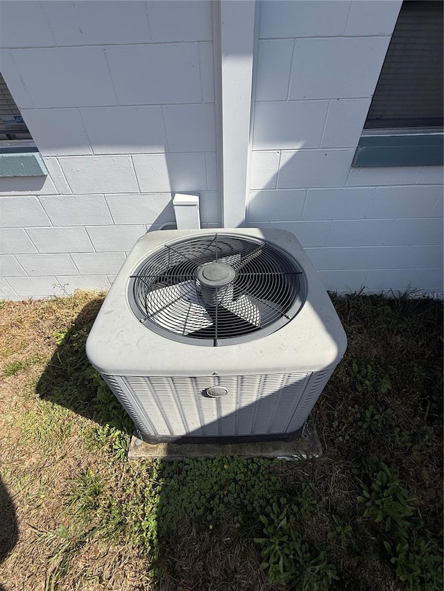 exterior details featuring concrete block siding and central AC unit