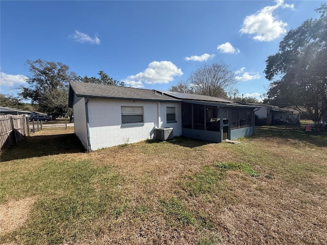 rear view of property featuring fence, central AC, a lawn, concrete block siding, and a sunroom