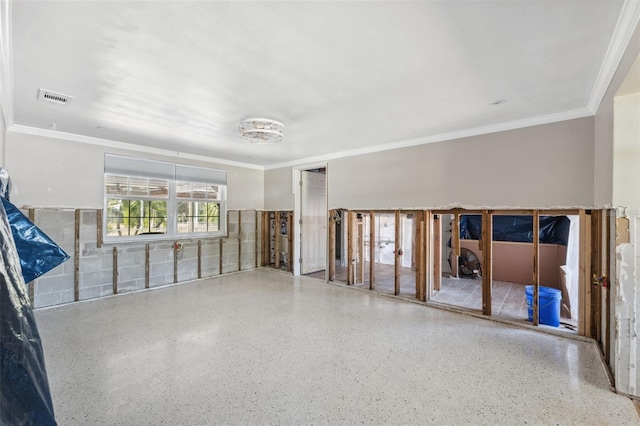 empty room featuring speckled floor, visible vents, and ornamental molding