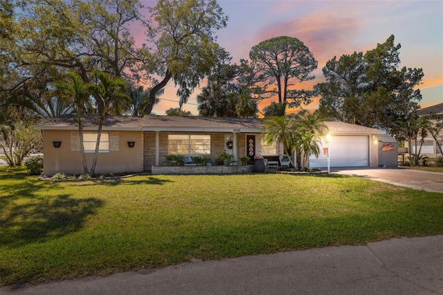 ranch-style house featuring stucco siding, a front yard, concrete driveway, and an attached garage