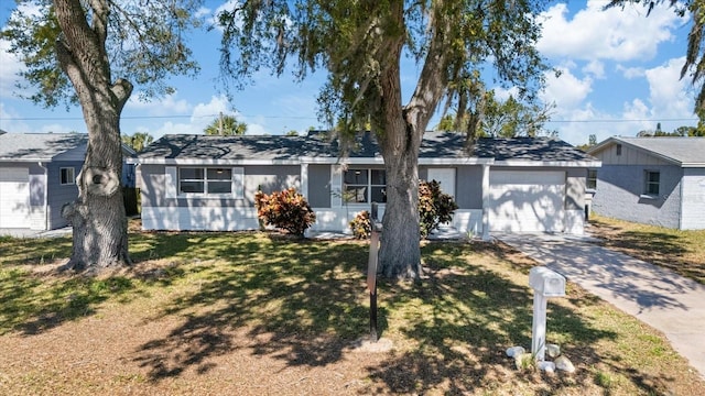 ranch-style house featuring concrete driveway, an attached garage, and a front yard