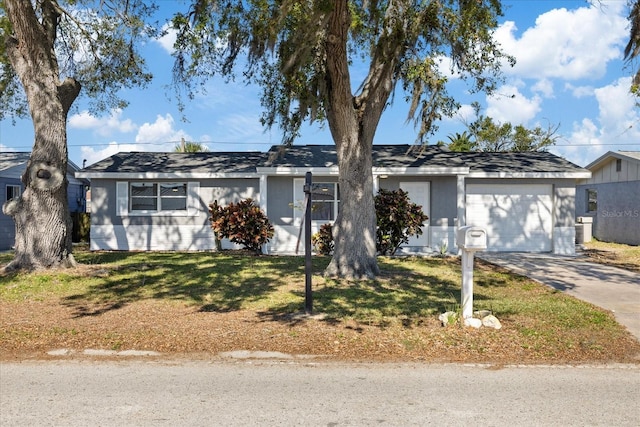 ranch-style home featuring concrete driveway, a garage, and a front lawn