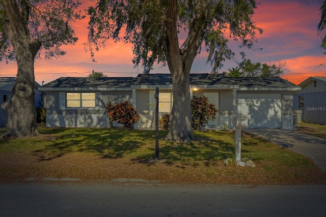 ranch-style house with a front yard, an attached garage, and driveway