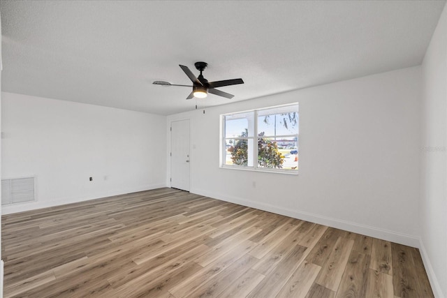 empty room featuring a ceiling fan, light wood-style floors, visible vents, and baseboards