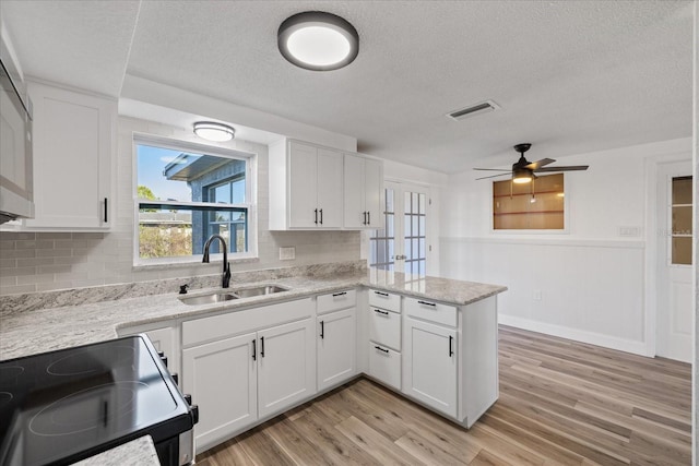 kitchen featuring range with electric stovetop, light wood-type flooring, a peninsula, and a sink